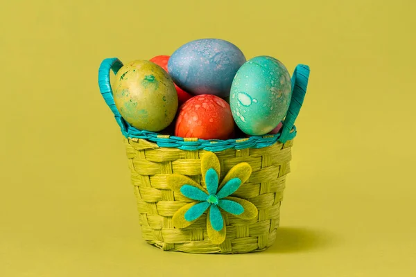 色彩艳丽的复活节彩蛋在绿色背景的手工篮子里 — 图库照片