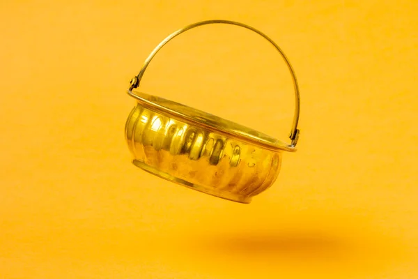 黄色の背景に落ちる空の黄金の鍋 — ストック写真
