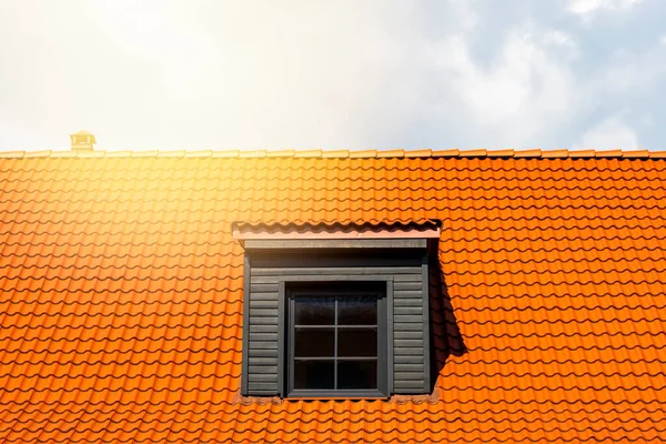 Renovated dormer window on the red clay ceramic tiles roof. Bright sunny day.