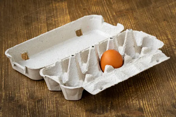 One Brown Egg Cardboard Egg Carton Wooden Background — Stockfoto