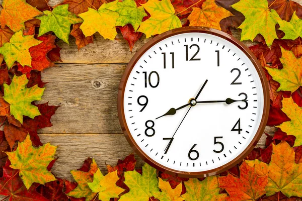 五彩斑斓的秋叶和挂在木背景上的挂钟 秋季时间 — 图库照片