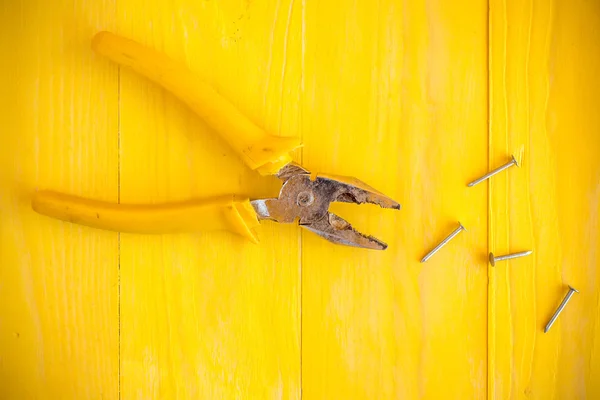 Kleště a nehty na povrchu žlutá — Stock fotografie