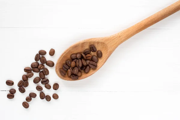 Koffie bonen op een lepel en houten achtergrond — Stockfoto
