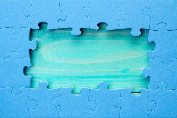 Puzzle pièces arrangées comme frontière autour de la surface en bois verte — Photo
