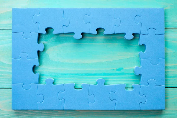 Puzzle frame on blue wooden surface — Stock Photo, Image