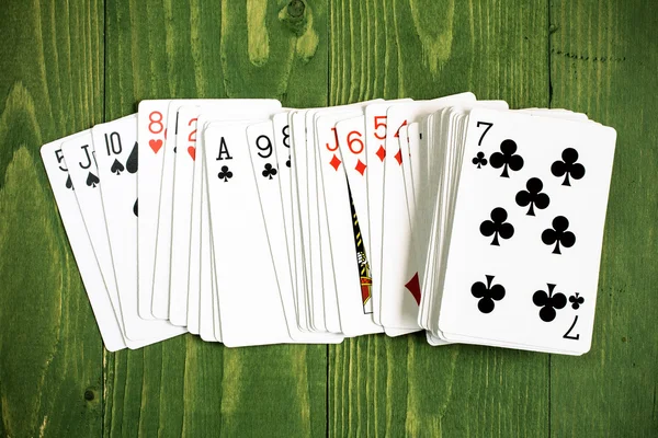 Playing cards on green wooden background — Stock Photo, Image