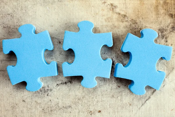 Three puzzle pieces on old canvas — Stock Photo, Image