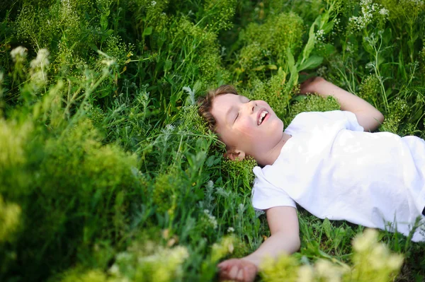 Niño está acostado en la hierba y soñando —  Fotos de Stock