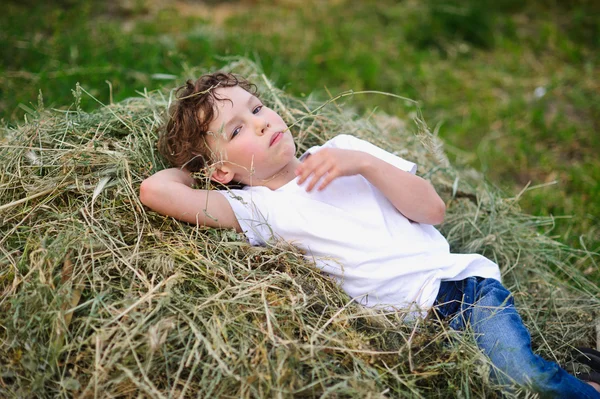 Niño acostado en el heno — Foto de Stock