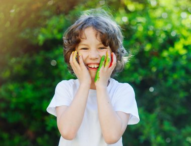 Çocuk boya ve ellerini yüzüne koyar