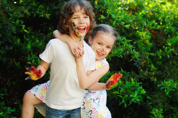 Niños abrazándose, con la cara y las manos pintadas — Foto de Stock