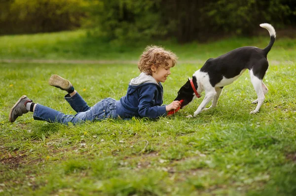 Niño jugando en el parque con un perro — Foto de Stock