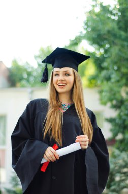 Bir diploma ile mezun gülüyor.