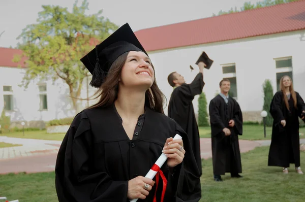 Gelukkig afgestudeerd met een diploma in de hand te kijken naar de hemel — Stockfoto
