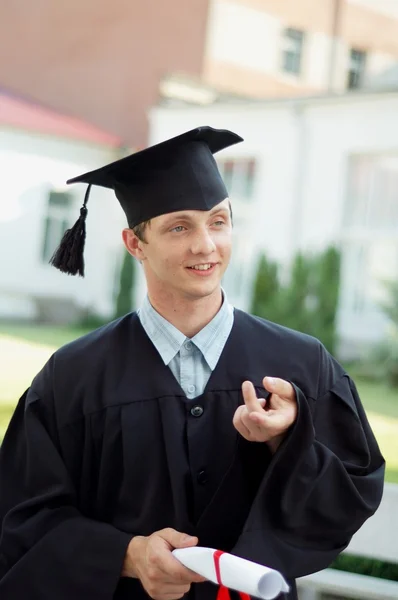 The graduate with a diploma in hand and black mantle — Stock Photo, Image