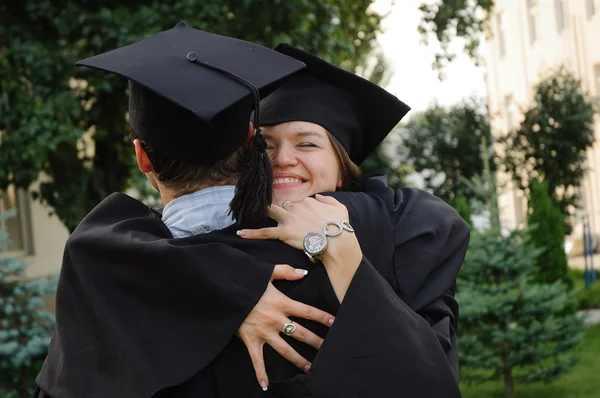 Menina graduada abraçando seu colega de classe — Fotografia de Stock