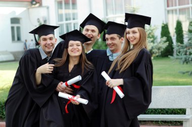 Group of laughing university graduates with diplomas in their hands clipart