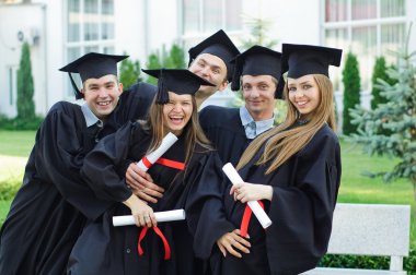 Group of laughing graduates with diplomas in their hands clipart