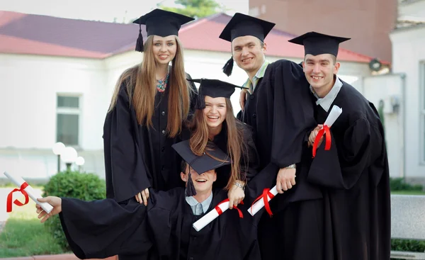 Grupo de graduados felizes com diplomas em suas mãos — Fotografia de Stock