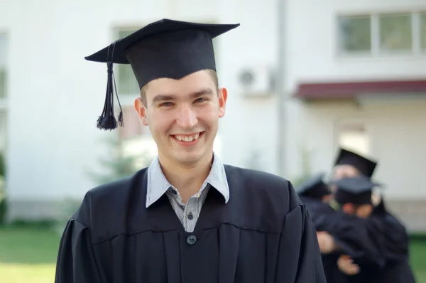 Выпускник в черной мантии с красивой улыбкой — стоковое фото