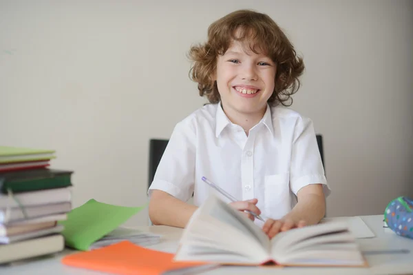 Мальчик сидит за столом и делает домашнее задание — стоковое фото