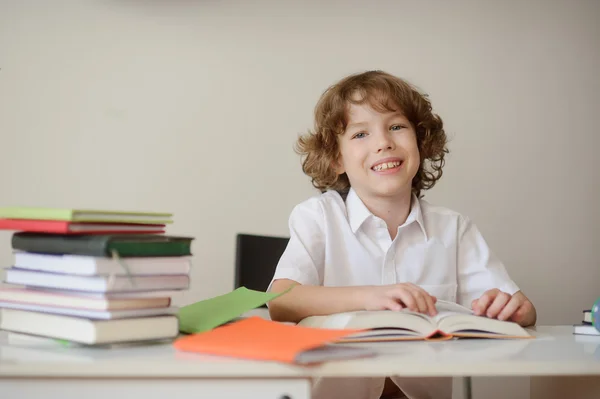 Улыбающийся мальчик сидит за школьным столом — стоковое фото