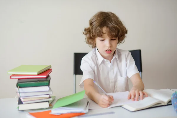 Elementary school student sitter vid ett skrivbord gör läxor. — Stockfoto