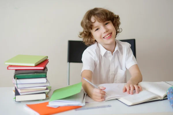Schoolboy in the classroom writing something — Stock Photo, Image