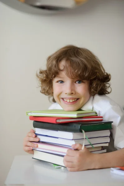 Der Junge drückt sich einen Stapel Bücher auf die Brust — Stockfoto