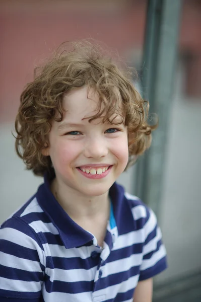 Menino bonito em uma camisa listrada está sorrindo alegremente . — Fotografia de Stock