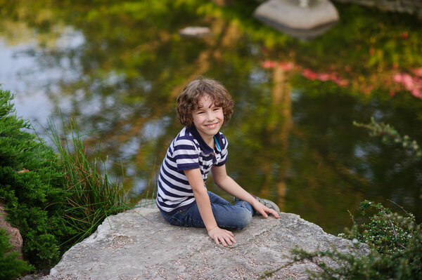 Boy sits on a large boulder at the lake