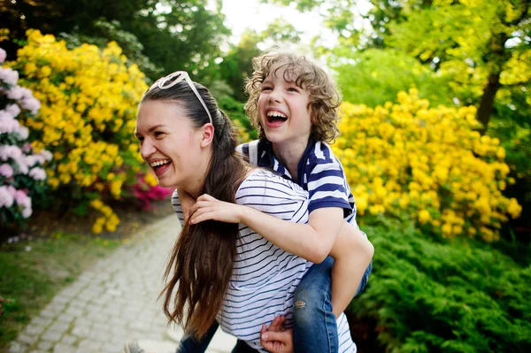 Young woman gave boy a piggyback ride — Zdjęcie stockowe