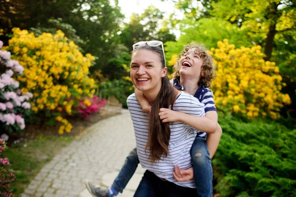 Meisje spelen met zijn jongere broer in de tuin — Stockfoto