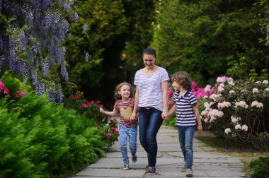Genç Anne parkta evli ve iki çocuk yürüyor.