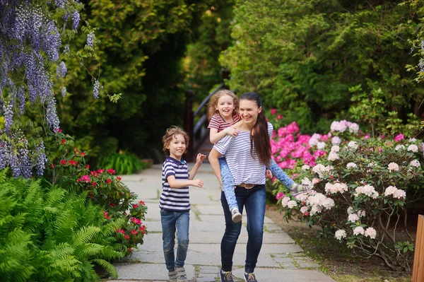 Moeder met twee kinderen op een wandeling in de weelderige tuin — Stockfoto