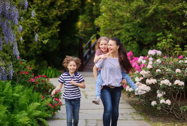 Jonge vrouw met haar twee kinderen lopen in een zomertuin — Stockfoto