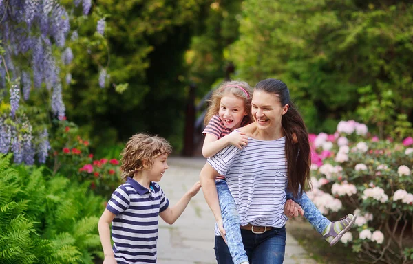 Moeder met de kinderen in een weelderige zomertuin — Stockfoto