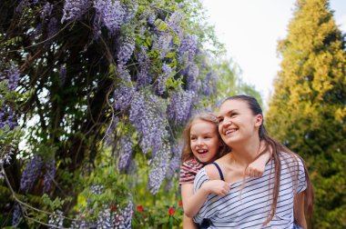 Kızı olan genç kadın bahçede yürümek.