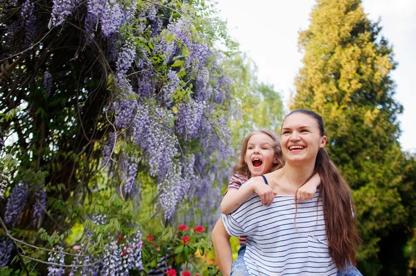 Jonge vrouw met een klein meisje in de bloementuin. — Stockfoto