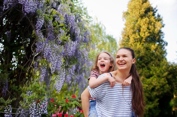 Jonge vrouw met een dochter wandeling in de tuin. — Stockfoto