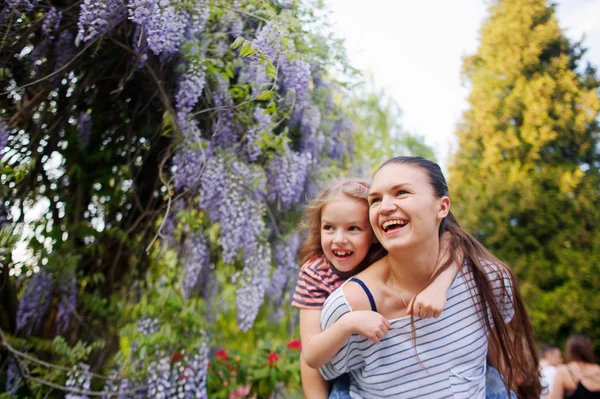 Jonge vrouw met een klein meisje in de bloementuin. — Stockfoto