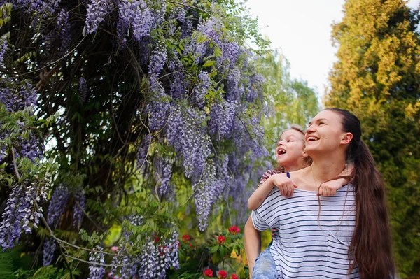 Jonge vrouw met dochter in een bloemrijke park — Stockfoto