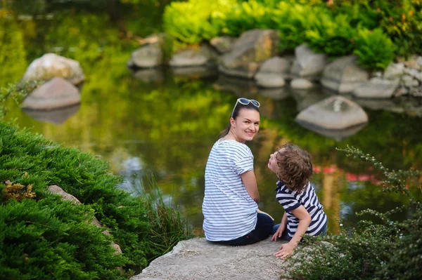 Moeder en zoon rustend op de oever van de vijver — Stockfoto