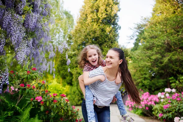 Kızı olan genç kadın bahçede yürümek.
