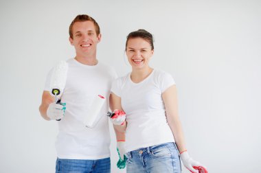 Young cheerful couple with rollers in hands on a white background.
