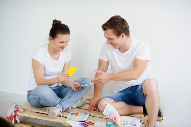 Young people select color for coloring of walls in the room.
