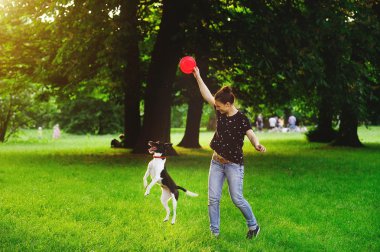 Genç kadın köpeğini bir parkta oynarken.