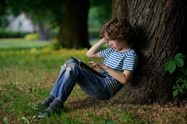 Pojke på 8-9 år med entusiasm är engagerad på tabletten. — Stockfoto