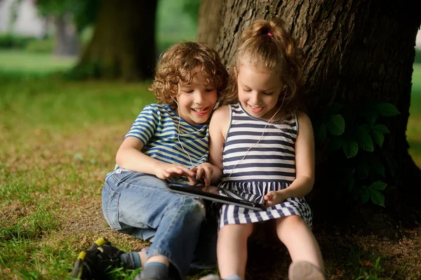 Brother and sister of 8-9 years play with passion on the tablet. — Stock Photo, Image