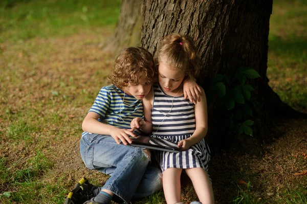 Twee kinderen van 7 tot 8 jaar zitten hebben geneigd over het scherm van de laptop. — Stockfoto